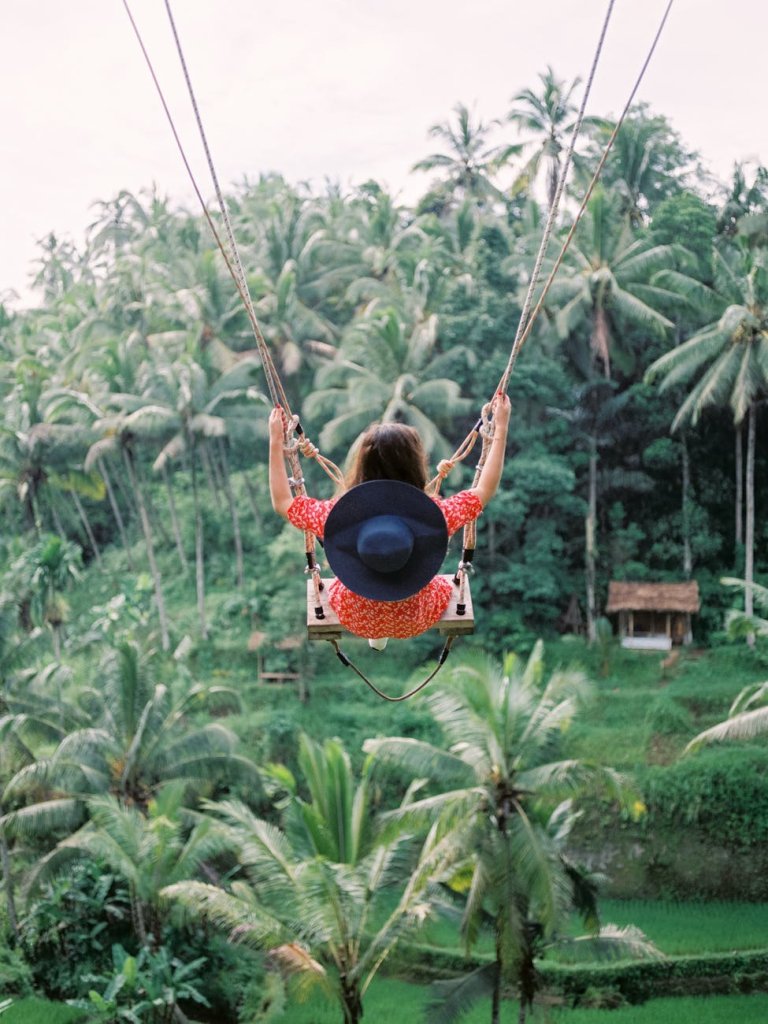 woman swinging on swing with view of tropical forest