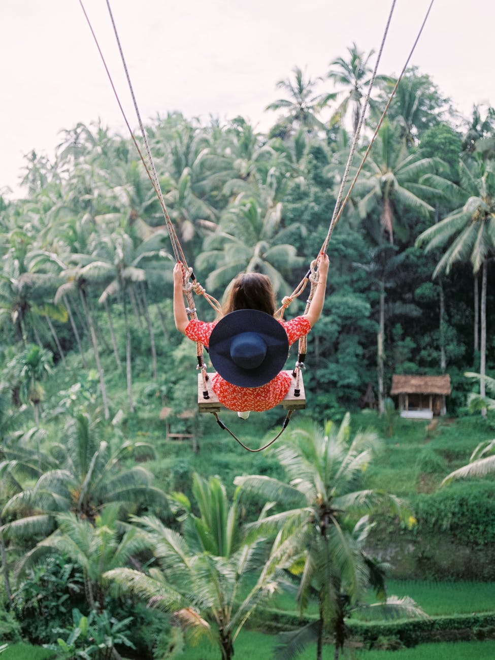 woman swinging on swing with view of tropical forest